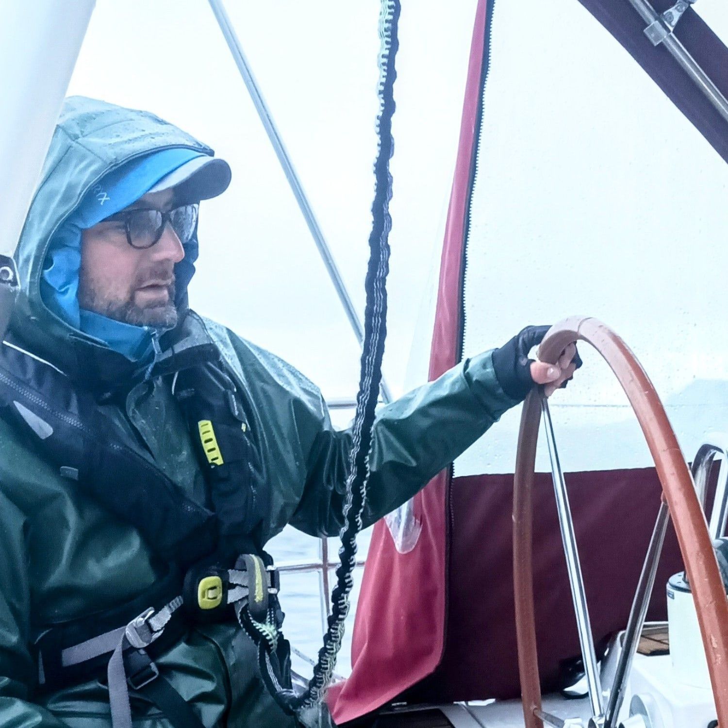 Gabriel Cardon at the helm in foul-weather gear, on a foggy crossing to Norway.
