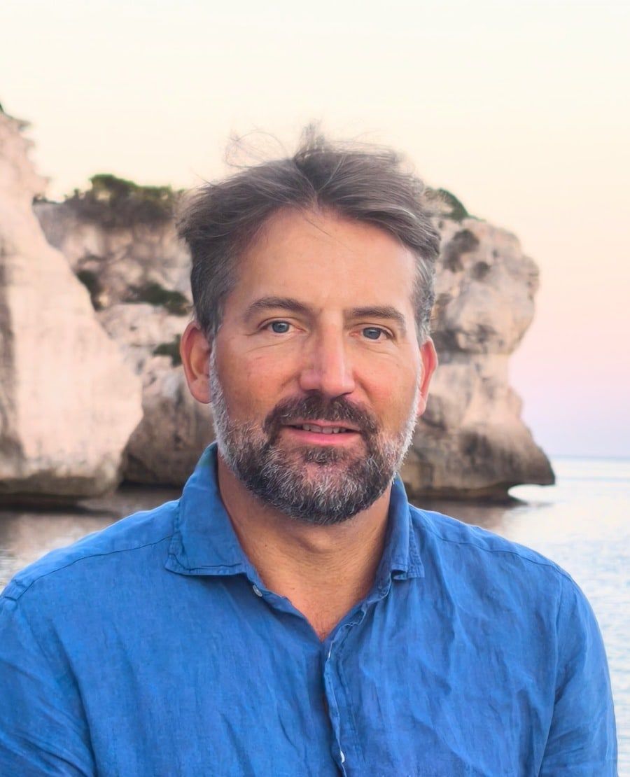 Gabriel Cardon, coach and professional skipper, in a blue shirt by the sea in Menorca.