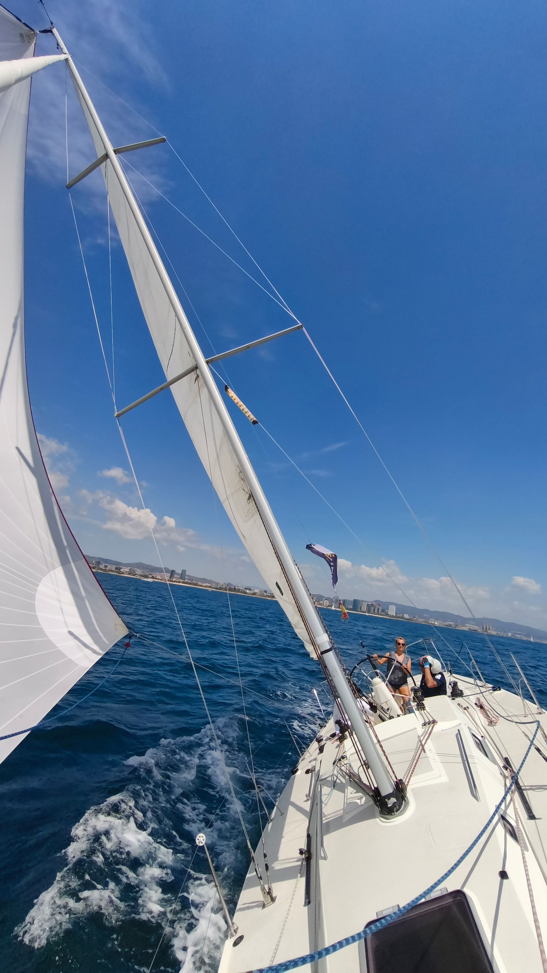 A heeling sailboat: one person helms while another works the winch.